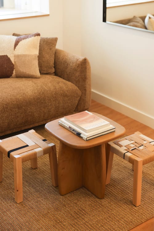Wooden coffee table with books in Sea'Ya Villas living room, Cascais, with tan sofa and woven stools.