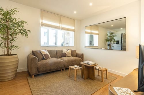 Modern living room at Sea'Ya Villas Cascais with gray sofa, mirror, bamboo plant, and wooden furniture