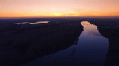 Vue du coucher de soleil sur la campagne de Sennely depuis La Grange Aux Etangs avec rivière sinueuse et paysage forestier