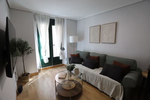 Elegante estudio en Madrid con sofá verde, luz natural y decoración minimalista moderna en la calle Colón