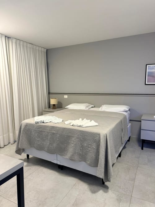 Quarto moderno de chalé na JT Prime Alojamentos com camas de solteiro, cortinas creme e vista para a piscina no Brasil