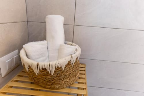 Cestino con articoli da bagno, asciugamani bianchi e rotolo di carta presso l'Aurum Nolana Suites a Pompei