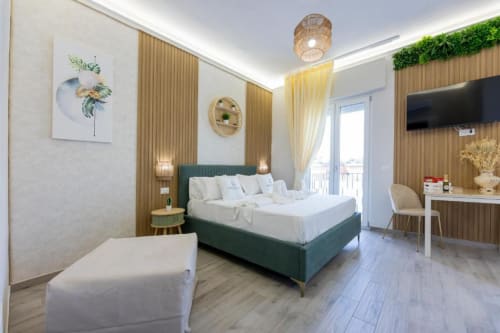 Camera Tripla Executive moderna presso Aurum Nolana Suites a Pompei con letto verde, balcone, scrivania e vista montagna