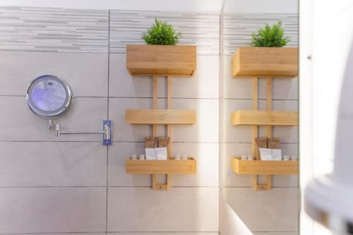 Elegante ripiano del bagno con organizer in legno, piante in vaso e prodotti per il bagno nella Deluxe Double Room dell'Aurum Nolana Suites
