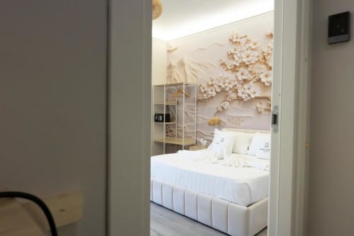 Elegante camera da letto regale presso Aurum Nolana Suites a Pompei con biancheria bianca, decorazioni murali e vista sul Vesuvio