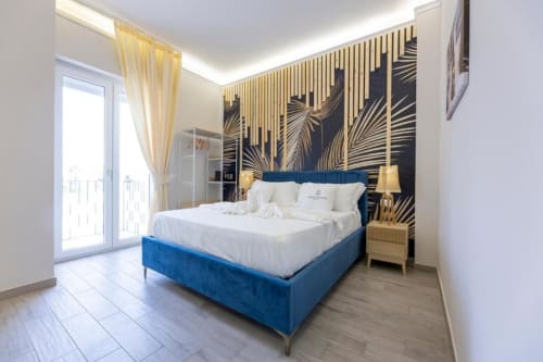 Lussuosa Suite Deluxe Doppia presso Aurum Nolana Suites a Pompeii con letto in velluto blu, parete con foglia d'oro e vista sulla città