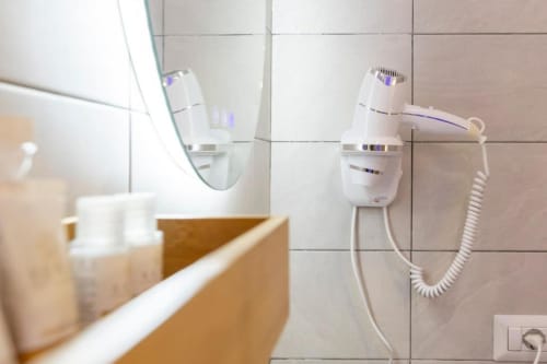 Phon bianco e articoli da bagno montati sulla parete del bagno nella camera d'hotel Aurum Nolana Suites Pompei