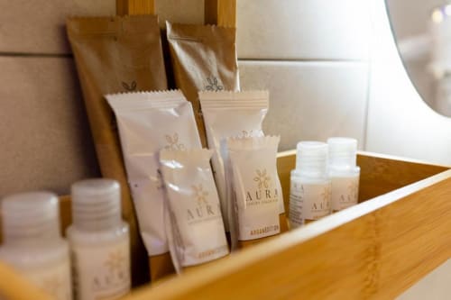 Esposizione di amenities AURA su scaffale in legno presso Aurum Nolana Suites a Pompei con prodotti da bagno e articoli da toilette