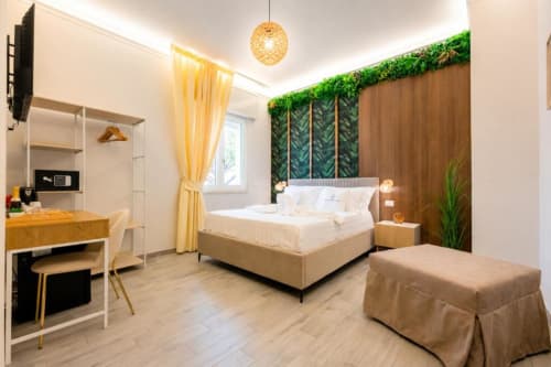 Camera tripla moderna presso Aurum Nolana Suites a Pompei con vista montagna, letto beige, tende gialle e accenti verdi lussureggianti