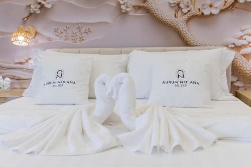 Lussuoso letto king size presso Aurum Nolana Suites a Pompei con arte di asciugamani a forma di cigno, cuscini ricamati e soffitto decorativo