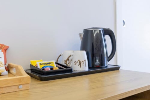 Bollitore elettrico nero e tazza di caffè sulla scrivania in legno presso Aurum Nolana Suites a Pompei, Italia