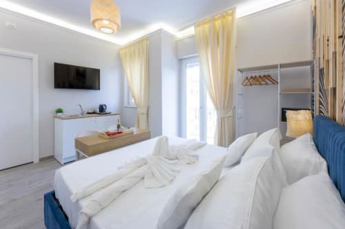 Luminosa Doppia Deluxe all'Aurum Nolana Suites di Pompei con biancheria bianca, balcone con vista città, TV, angolo cottura e arredamento moderno