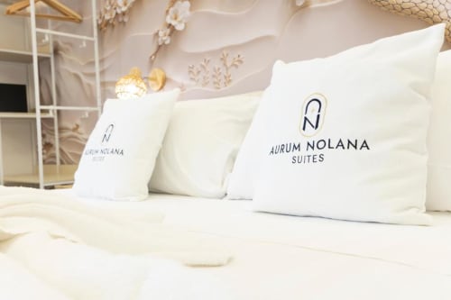 Lussuosi cuscini Aurum Nolana Suites su letto king nella camera dell'hotel Pompei con vista sul Vesuvio