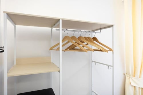 Guardaroba bianco con appendiabiti in legno nella Triple Room dell'Aurum Nolana Suites di Pompei