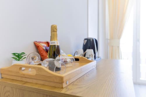 Vassoio di benvenuto con bottiglia di champagne, bicchieri, piccola pianta e cuscino rosso nella King Room di Aurum Nolana Suites, Pompei