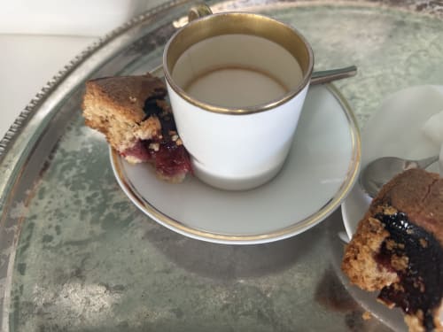 Service à café élégant à l'Hidden Bay Hotel avec parts de pâtisserie et cappuccino sur plateau vintage
