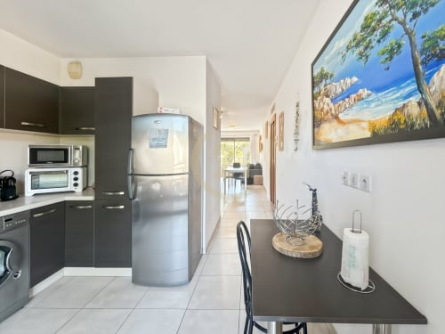 Cuisine moderne de l'appartement L'Île-Rousse près de la plage de Calvi avec mobilier sombre, électroménagers inox et espace repas