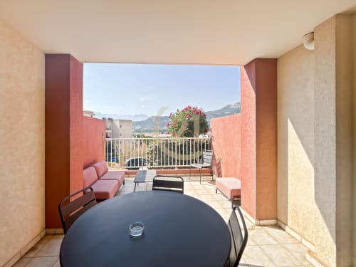 Terrasse ensoleillée aux murs rouges, coin détente et vue sur les montagnes à L'Île-Rousse, Corse