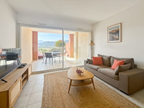 Appartement T2 moderne à L'Île-Rousse, salon meublé avec TV, canapé et balcon vue montagne