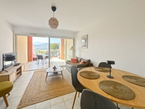 Appartement moderne à L'Île-Rousse avec séjour et cuisine ouverts, vue montagne depuis la terrasse