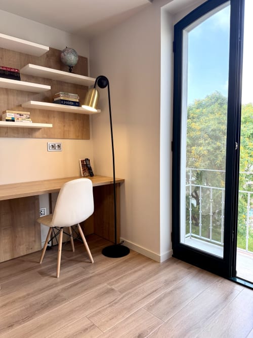 Espace de travail moderne au RIA CENTRUM Aveiro avec bureau en bois, chaise blanche, lampadaire arc, étagères et porte vitrée donnant sur le canal