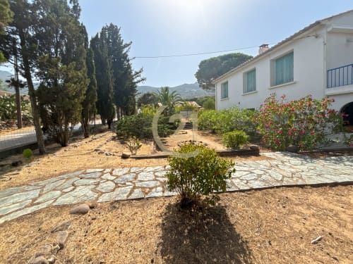 Cour de villa méditerranéenne à Calvi, Corse : terrasse en pierre, fleurs colorées et façade blanche