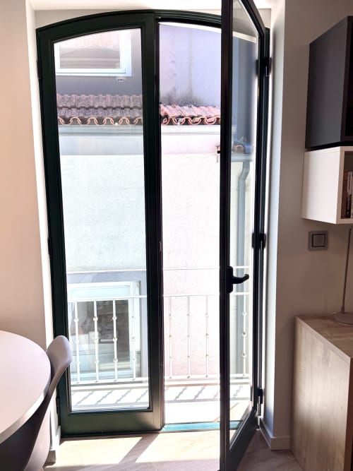 Porte-fenêtre vitrée à cadre noir de l'hôtel RIA CENTRUM à Aveiro, donnant sur une cour aux toits de terre cuite