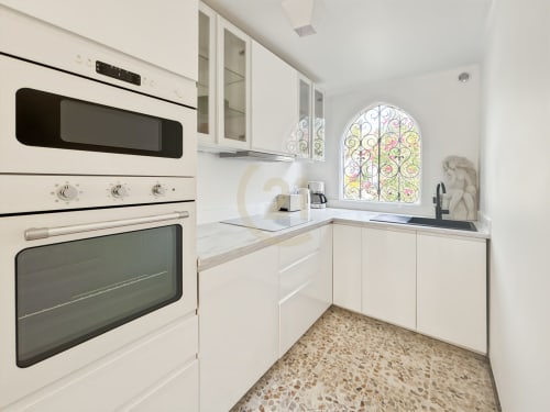 Cuisine blanche moderne avec vitrail, électroménagers intégrés et sol en terrazzo dans l'appartement de L'Île-Rousse