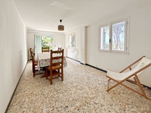 Salle à manger lumineuse avec sol en terrazzo, chaises en bois, transats et vue sur le jardin de l'appartement Calvi à L'Île-Rousse