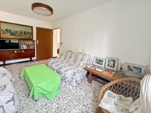 Spacieux séjour dans un authentique appartement calvi avec canapé à motifs, photos encadrées, meubles en bois et vert éclatant