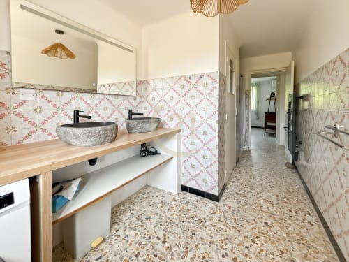 Salle de bains contemporaine avec vasques en pierre, carrelage rose motifs, sol en terrazzo dans l'appartement de Calvi