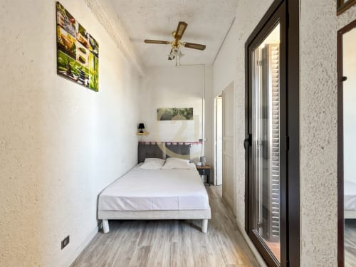 Chambre moderne à L'Île-Rousse avec vue mer, lit blanc, ventilateur et accès terrasse