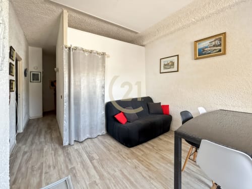 Séjour T3 avec vue sur mer à L'Île-Rousse, canapé noir, table à manger et mobilier contemporain