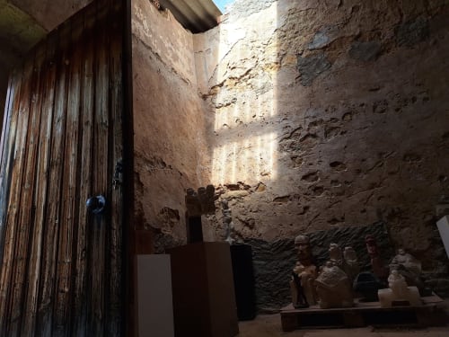Patio histórico de piedra en Casa Llobera 1792 en La Pobla de Cèrvoles con puerta de madera y esculturas de terracota