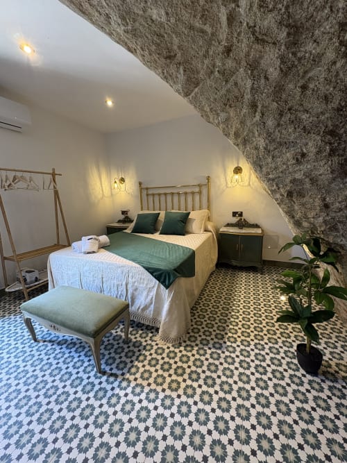 Dormitorio Casa Cueva Esmeralda con ropa de cama verde, techo de piedra y piso decorativo en Setenil de las Bodegas