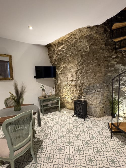 Sala de estar de Casa Cueva Esmeralda con muros de piedra vista, azulejos decorativos y mobiliario moderno en Setenil de las Bodegas