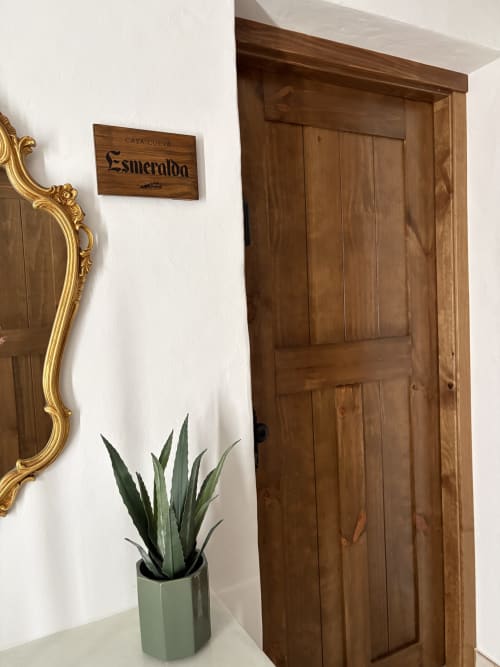 Entrada de Casa Cueva Esmeralda con puerta de madera, espejo dorado y planta suculenta en Setenil de las Bodegas