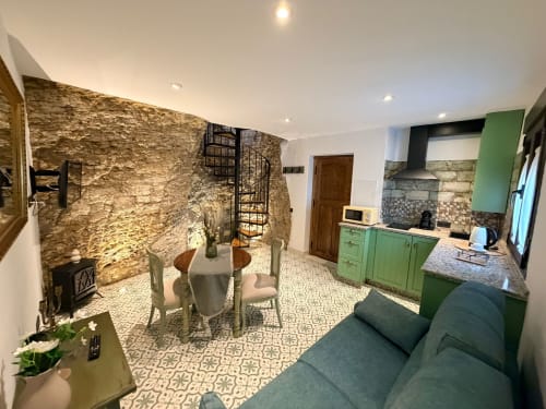 Apartamento en cueva moderna de Setenil con cocina verde, paredes de piedra, comedor y sala de estar