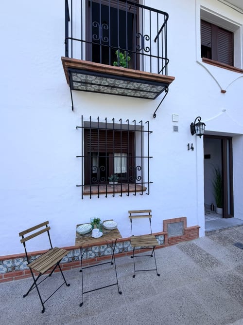 Encantador patio de La Joya de Setenil con muros encalados, balcones de hierro forjado y asientos al aire libre