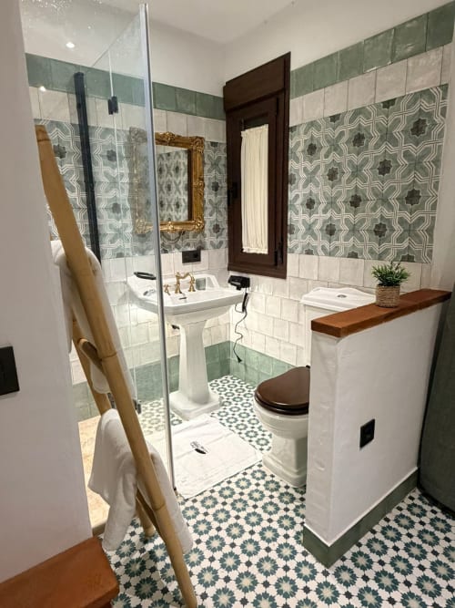 Baño moderno en Casa Cueva Esmeralda con azulejos verde, lavamanos pedestal y ducha con mampara de vidrio