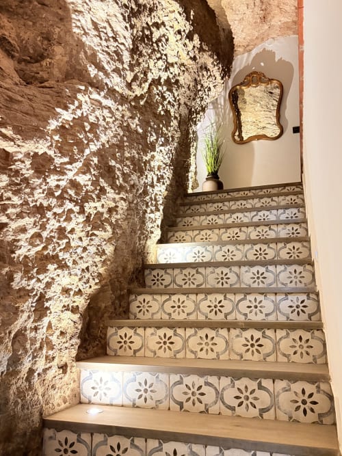 Escalera rústica de casa cueva con azulejos decorativos y muros de piedra encalada en La Joya de Setenil