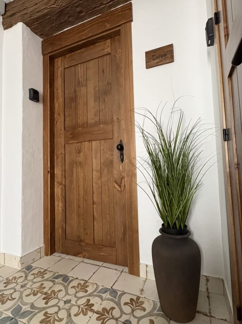 Puerta de entrada de madera a Casa Cueva Zafiro en La Joya de Setenil, con azulejos decorativos y maceta
