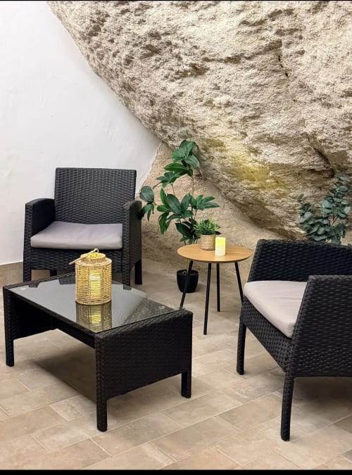 Zona de descanso en patio moderno con mobiliario de mimbre negro en el hotel cueva La Joya de Setenil, España