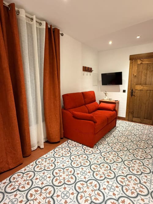Apartamento Rubí en La Joya de Setenil con sofá rojo, suelos de azulejos decorativos y comodidades modernas