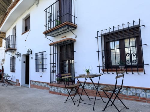 Encantador patio encalado de La Joya de Setenil con balcones de hierro forjado, mobiliario exterior y estilo andaluz tradicional