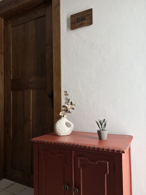 Mueble de barro cocido con jarrón blanco y planta suculenta en Casa Cueva Rubí de La Joya de Setenil