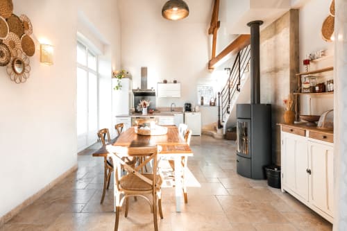 Salle à manger fermette au Hameau de Céline avec table en bois, chaises tressées et poêle en bois noir