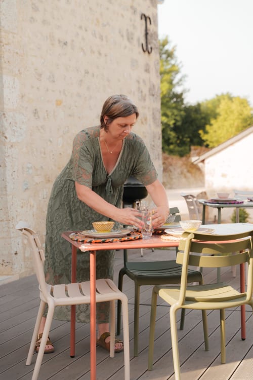 Femme dressant une table sur la terrasse du gîte Le Hameau de Céline en Landes-le-Gaulois, France