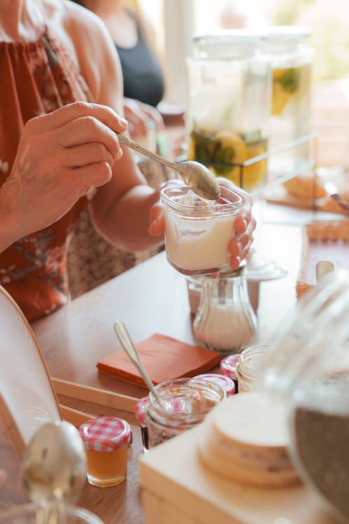 Femme préparant de la confiture maison à la table du petit-déjeuner, Gîte Le Hameau de Céline B&B à Landes-le-Gaulois