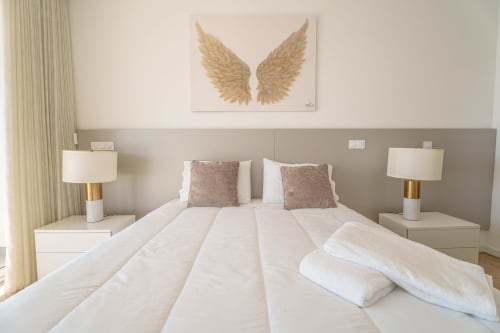 Modern bedroom at Suites Avenue Lux Apartments in Horta with gold angel wing art and white bedding